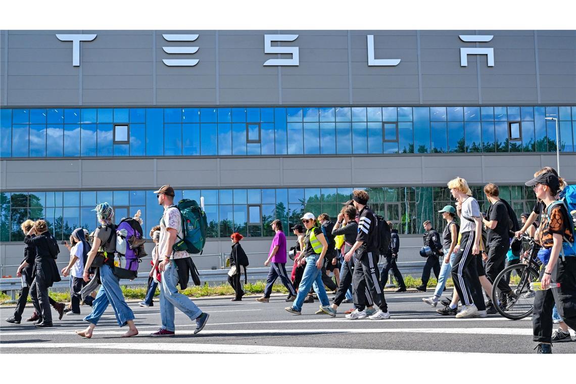 Teilnehmerinnen und Teilnehmer eines Protestmarschs laufen am Tesla-Werk vorbei.