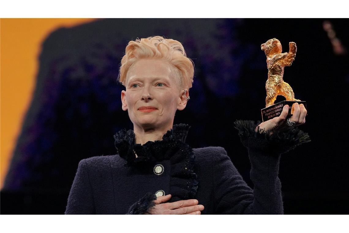 Tilda Swinton steht während der Eröffnung der Berlinale auf der Bühne und hält ihren goldenen Ehrenbär hoch.