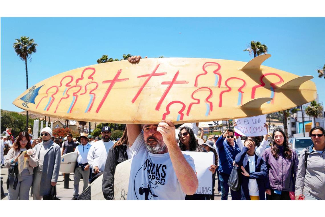 Todessymbole auf dem Surfbrett: Bei der Trauerfeier für die drei ermordeten US-Surfer demonstrieren Teilnehmer auch gegen das organisierte Verbrechen in Mexiko.