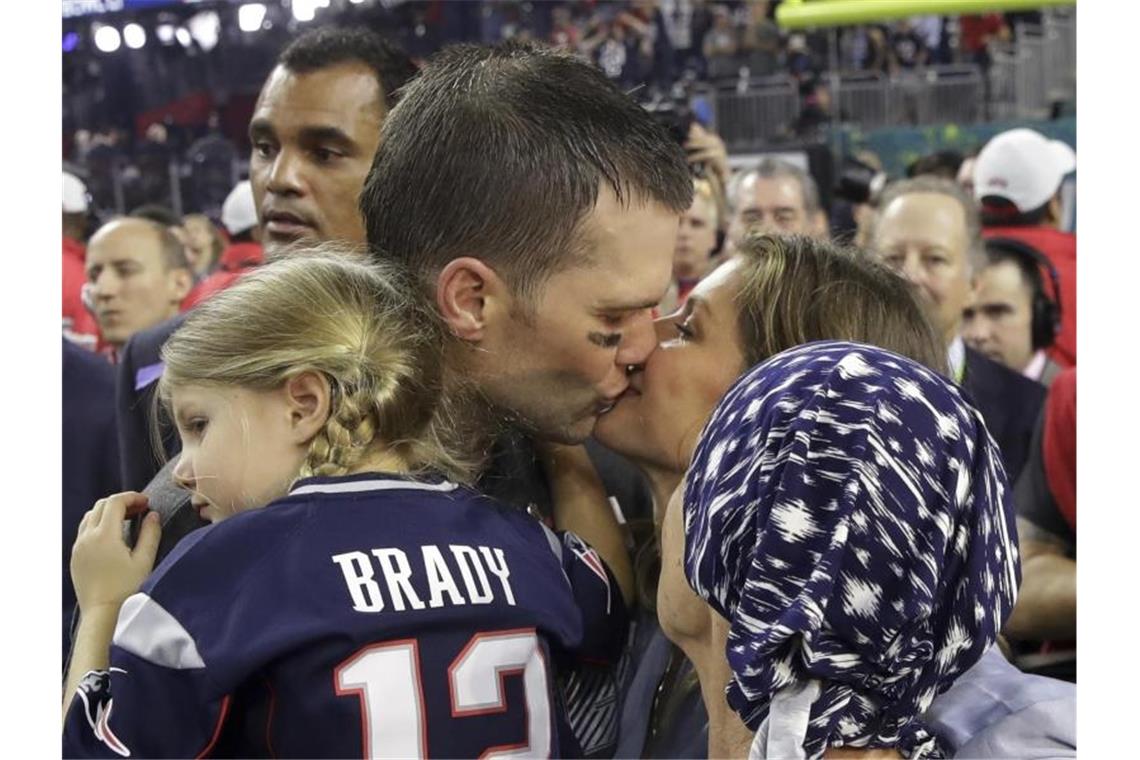 Tom Brady von den New England Patriots hält Tocher Vivian auf dem Arm und küsst seine Frau Gisele Bündchen, die Bradys Mutter Galynn (vorn) den Arm über die Schulter gelegt hat. Foto: Patrick Semansky/AP/dpa