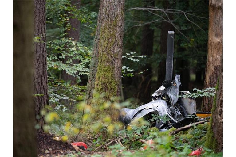 Trümmerteile eines Hubschraubers vom Typ Robinson R44 und Feuerlöscher liegen in einem Wald nahe der Grenze zu Hessen und Bayern. Foto: Sebastian Gollnow/dpa/Archivbild