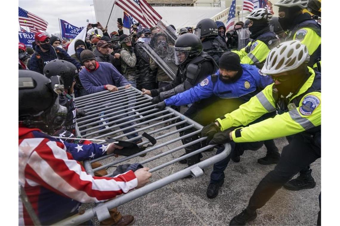 Ein Jahr nach Kapitol-Attacke: Bereits mehr als 700 Anklagen Trump-Anhänger versuchen, vor dem Kapitol durch eine Polizeiabsperrung zu brechen. Foto: John Minchillo/AP/dpa