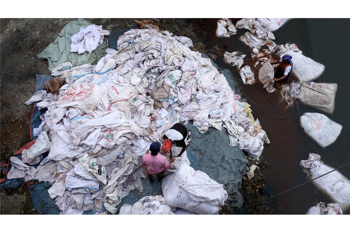 Umwelt und Existenz: Arbeiter reinigen kontaminierte Plastiksäcke im Turag-Fluss zur Wiederverwendung