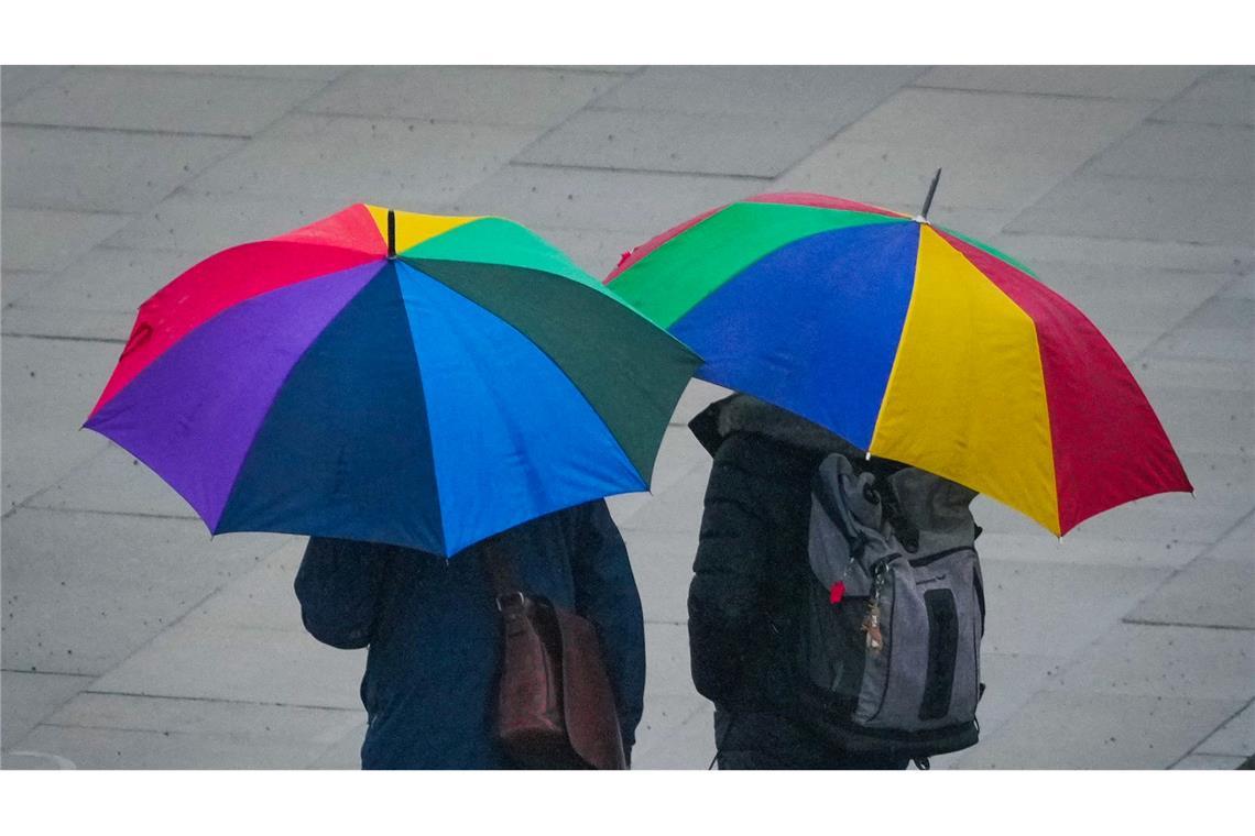 Unter bunten Regenschirmen suchen zwei Passanten Schutz vor leichtem Regen in der Potsdamer Innenstadt.