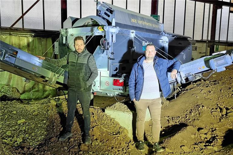 Unternehmer Alexander Rümke (rechts) und Vertriebsleiter Roberto Bruno vor der Siebmaschine in Halle 3. Der mobile Steinbrecher, der momentan vor der Halle steht, hat in etwa dieselben Ausmaße. Foto: Florian Muhl