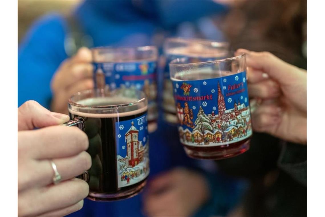 Vier Frauen stoßen auf dem Weihnachtsmarkt mit Glühwein an. Das Deutsche Weininstitut in Mainz stellt einen Trend zu höherwertigen Glühweinen fest. Foto: Patrick Seeger/dpa