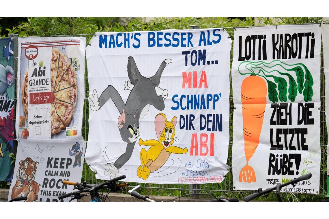 Von Freunden und Eltern gestaltete "Abi-Plakate" hängen am Zaun eines Gymnasiums in Frankfurt. In Hessen starten die schriftlichen Abiturprüfungen.