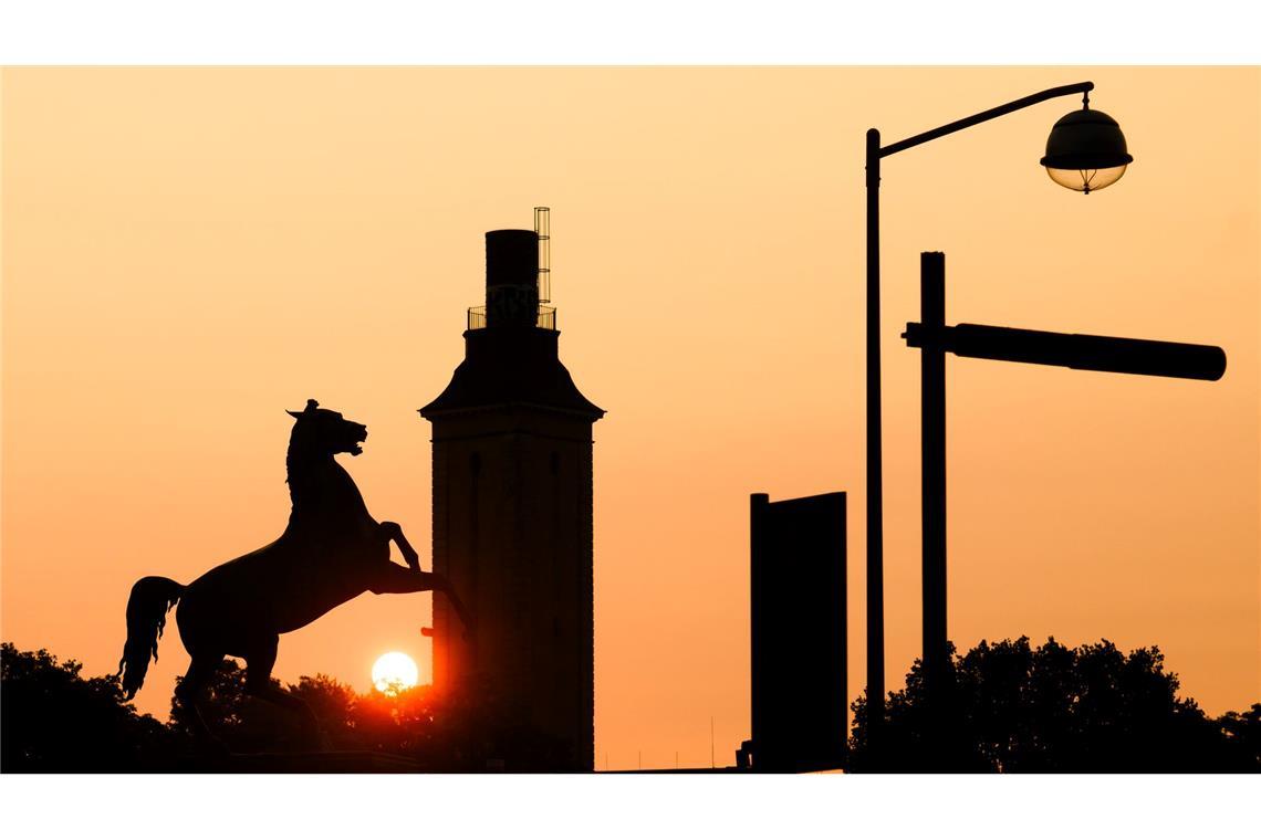 Vor dem in den Farben des Sonnenaufgangs getauchten Morgenhimmel hebt sich die Silhouette des Sachsenrosses vor dem Welfenschloss der Leibniz Universität Hannover ab.