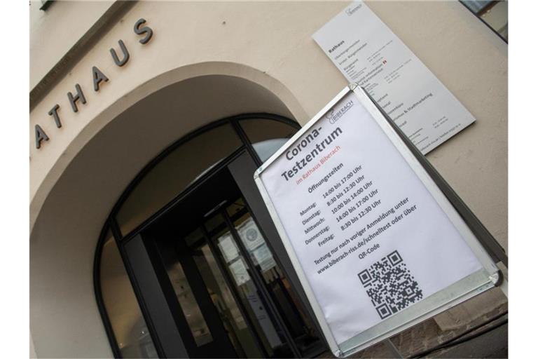 Vor dem Rathaus weist ein Schild auf das dort eingerichtete Corona-Testzentrum hin. Foto: Stefan Puchner/dpa