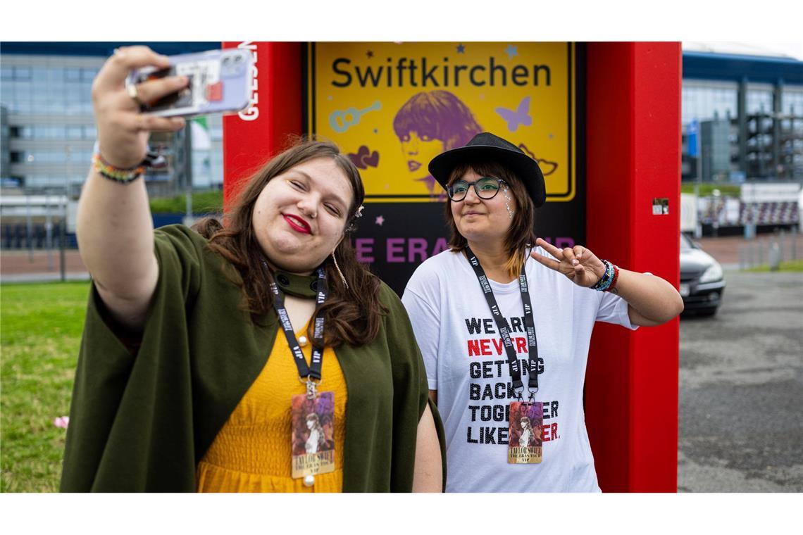 Vor dem Taylor Swift Konzert: Alessia aus Nordhorn und Melina aus Kassel, machen mit ihrem Smartphone ein Selfie vor einem umfunktionierten Ortsschild mit der Aufschrift: "Swiftkirchen". Am Abend findet das erste Taylor Swift-Konzert im Rahmen ihrer Eras-Tour in Deutschland statt.