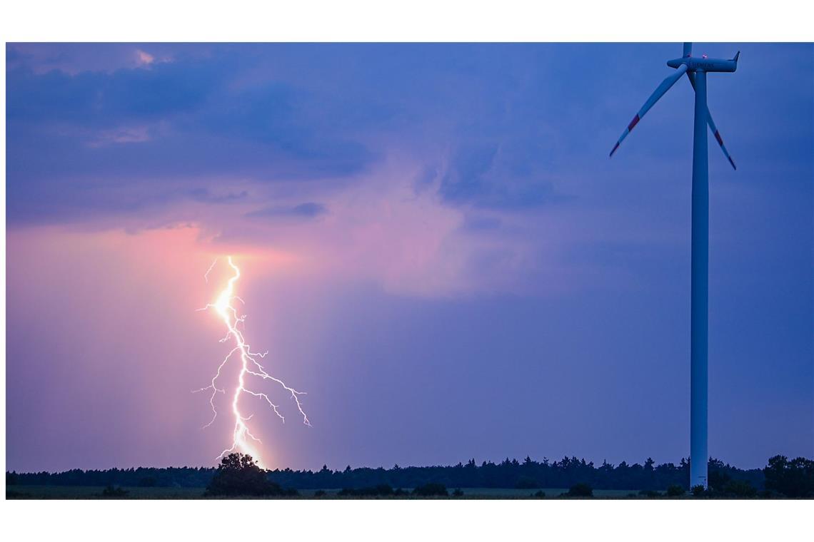 Während eines Gewitters erhellt ein Blitz den Nachthimmel mit einer Windenergieanlage im östlichen Brandenburg.