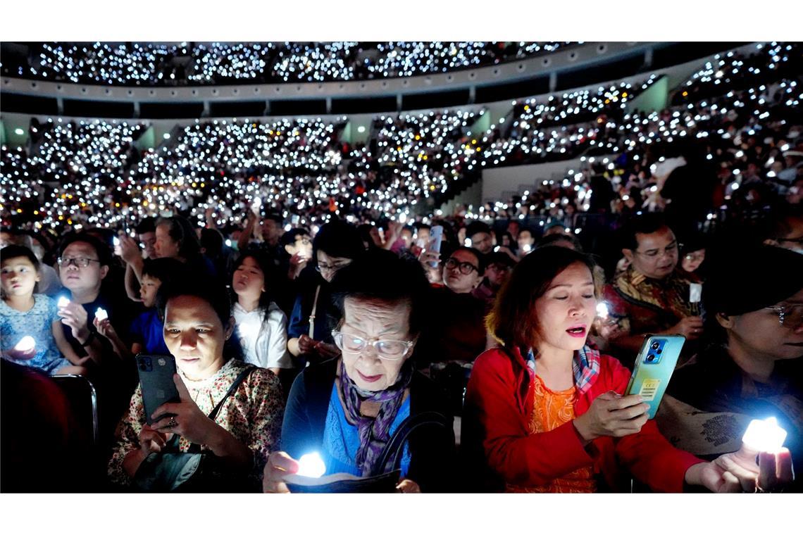 Weihnachten in Indonesien: Menschen halten elektrische Kerzen, während sie an einem Gottesdienst zu Heiligabend in Jakarta teilnehmen und  singen.