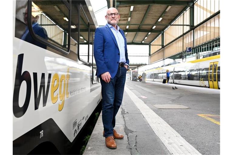 Winfried Hermann (Bündnis 90/Die Grünen) steht vor einem Regionalzug. Foto: Bernd Weißbrod/dpa/Archivbild