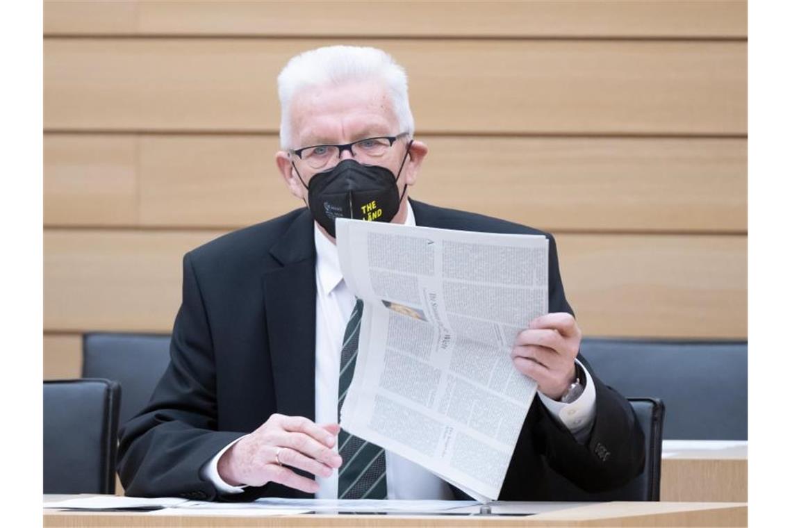 Winfried Kretschmann (Bündnis 90/Die Grünen) legt vor Beginn auf der Regierungsbank eine Zeitung ab. Foto: Bernd Weißbrod/dpa/Archivbild