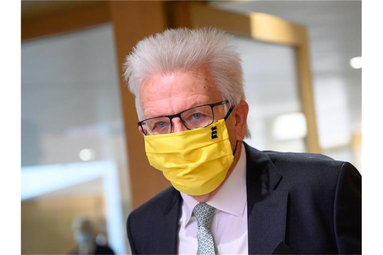 Winfried Kretschmann (Bündnis 90/Die Grünen) mit einem Mundschutz. Foto: Sebastian Gollnow/dpa/Archivbild