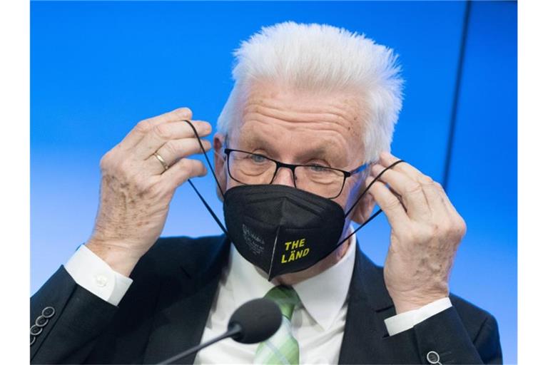 Winfried Kretschmann setzt sich nach einer Regierungs-Pressekonferenz eine Maske auf. Foto: Bernd Weißbrod/dpa