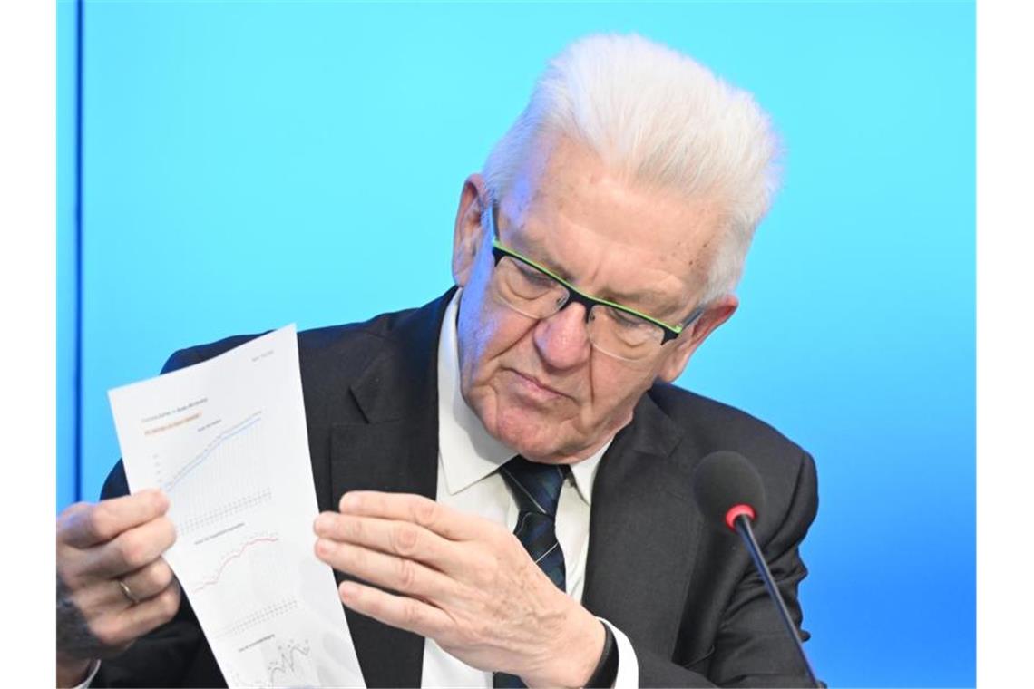 Winfried Kretschmann zeigt ein Blatt mit Corona-Tabellen auf der Regierungspressekonferenz. Foto: Bernd Weißbrod/dpa