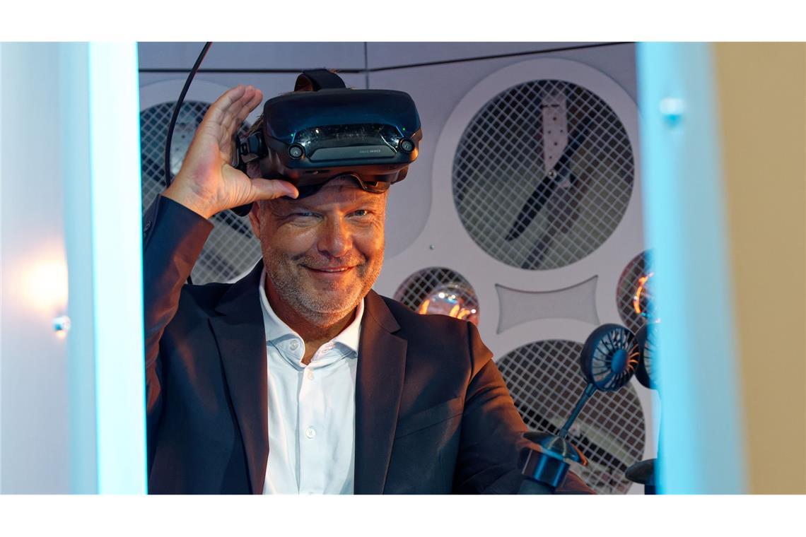 Wirtschaftsminister Robert Habeck (Grüne) steht bei einem Messerundgang bei der Computerspiele-Messe Gamescom 2022 in einem Simulator und trägt dabei eine Virtual-Reality-Brille.