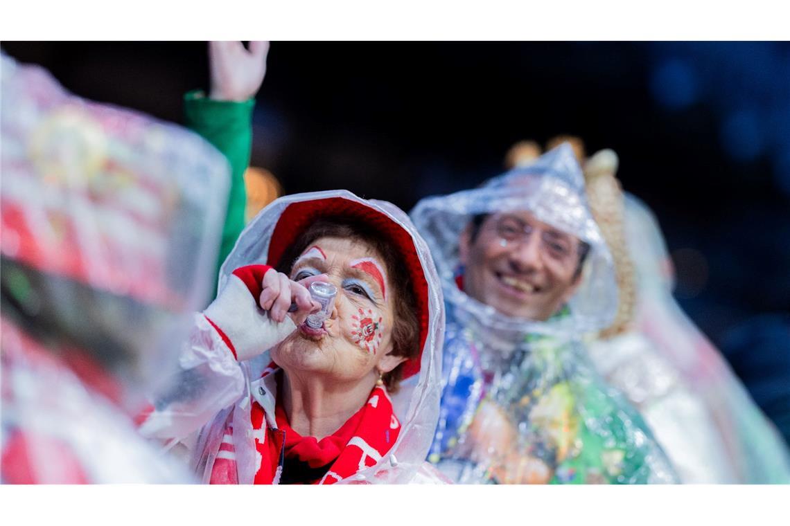 Wohl bekomm's! Karnevalisten mit Regenschutz feiern an Weiberfastnacht die Eröffnung des Straßenkarnevals auf dem Alter Markt in Köln.