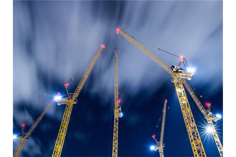 Wolken ziehen über Baukräne auf einer Großbaustelle hinweg. Foto: Silas Stein/dpa/Archivbild