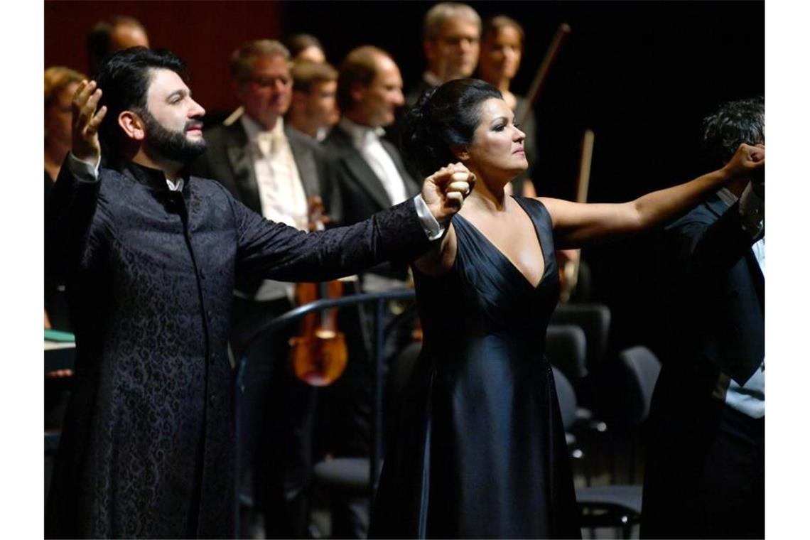 Yusif Eyvazov, Anna Netrebko und Dirigent Mario Armiliato halten sich beim Applaus die Hände. Foto: Barbara Gindl/APA/dpa/Archivbild