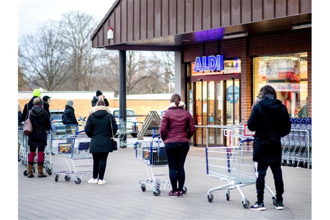 Handel fürchtet Warteschlangen vor Lebensmittelläden Zahlreiche Kunden warten auf die Öffnung einer Filiale von Aldi im Stadtteil Bult in Hannover. Foto: Hauke-Christian Dittrich/dpa
