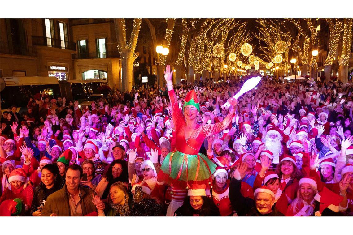 Zahlreiche Menschen in Weihnachtskostümen tanzen in der Avenida Passeig del Born auf Mallorca.