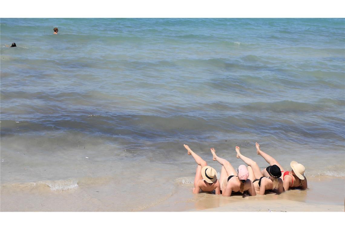 Zu viert entspannt am Strand - Touristen genießen den Sommer in Arenal.