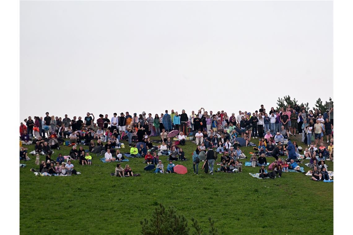 Zuschauer sitzen auf dem Aussichtshügel Riemer Park beim ersten von zehn Konzerten der britischen Sängerin Adele in München.