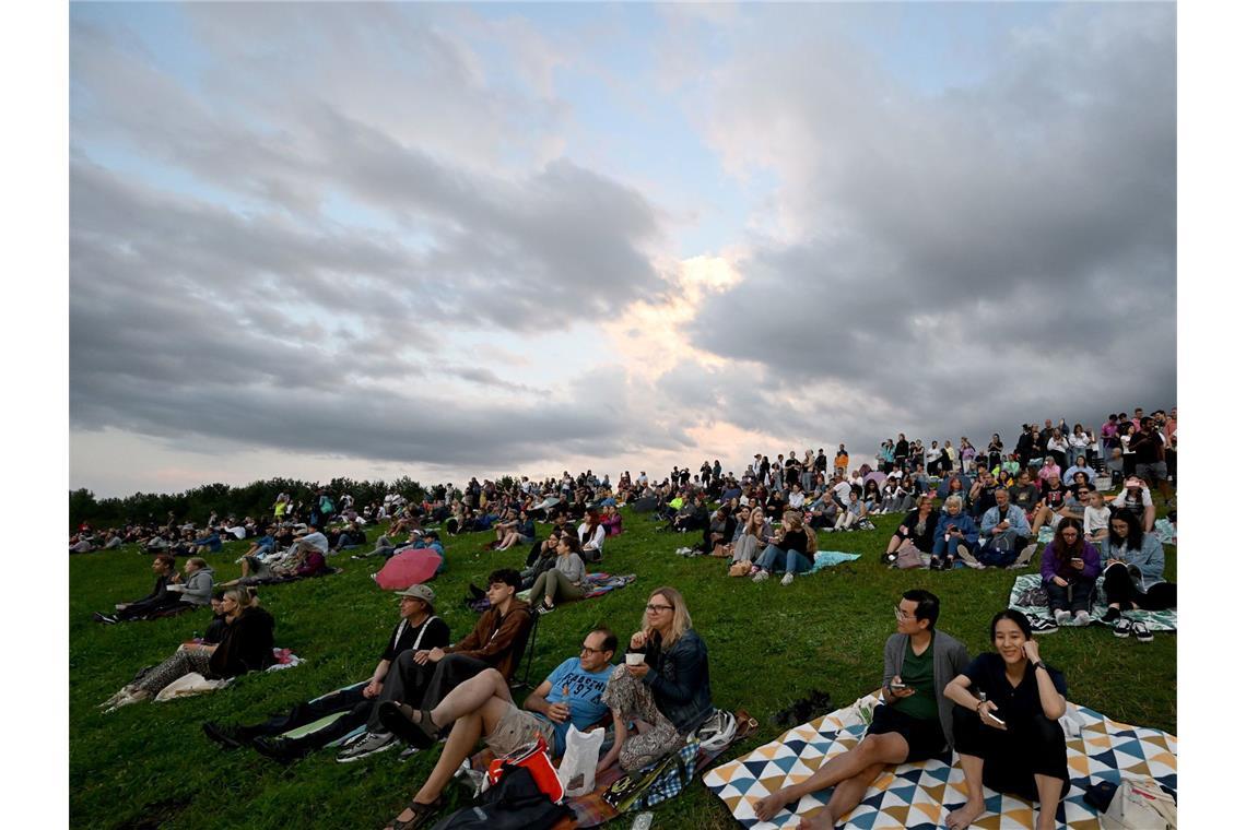 Zuschauer sitzen auf dem Aussichtshügel Riemer Park beim ersten von zehn Konzerten der britischen Sängerin Adele in München.