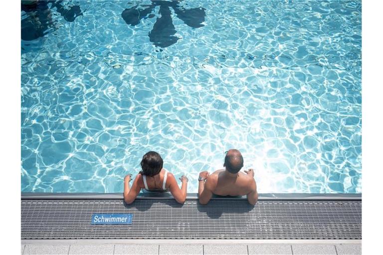 Zwei Badegäste stehen in einem Freibad im Schwimmbecken. Foto: Sebastian Gollnow/dpa/Symbolbild