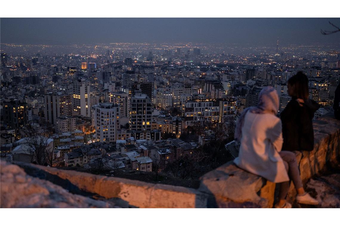 Zwei Frauen blicken nach Sonnenuntergang auf die Millionenmetropole Teheran.