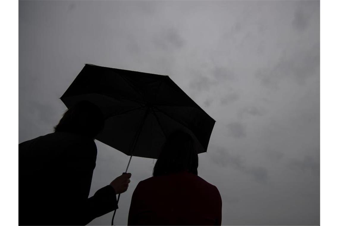 Zwei Frauen stehen unter einem Regenschirm. Foto: Marijan Murat/dpa