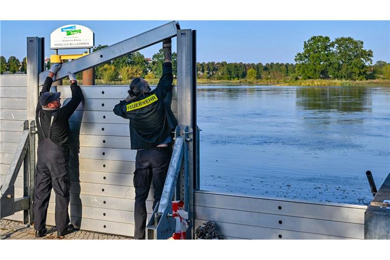 Zwei Kameraden der Freiwilligen Feuerwehr errichten eine mobile Hochwasserschutzwand am deutsch-polnischen Grenzfluss Oder.