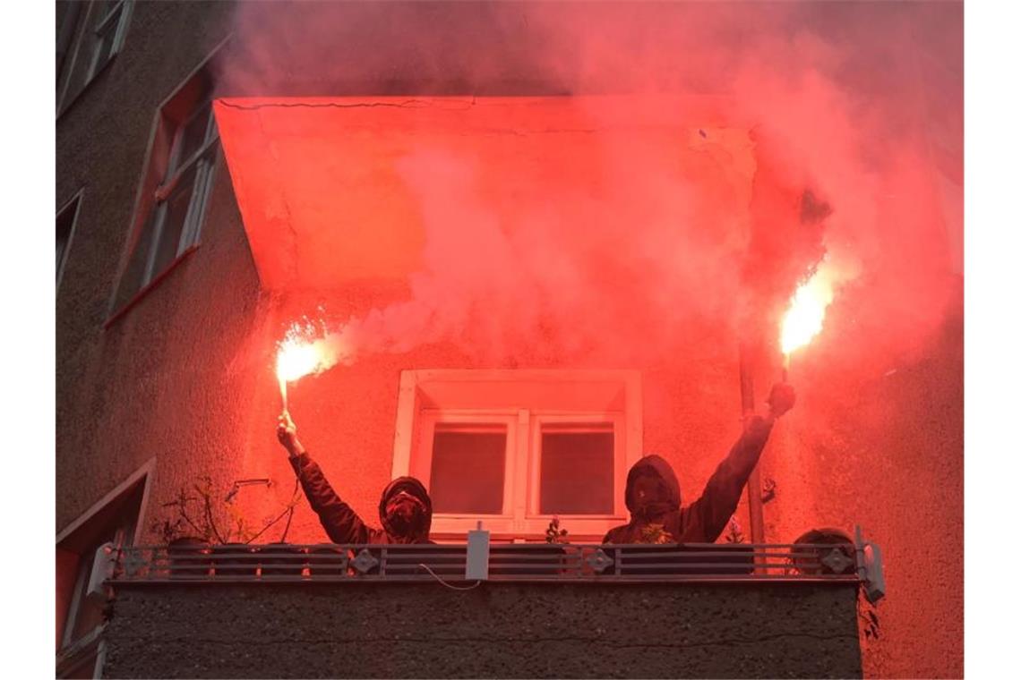Berlin vor dem 1. Mai - Friedlicher Protest im Wedding Zwei Personen halten während einer Demonstration linker und linksradikaler Gruppen durch Wedding zwei brennende Rauchfackeln auf einem Balkon. Foto: Christophe Gateau/dpa