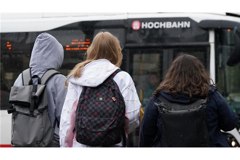 Zwei Schülerinnen und ein Schüler warten in Hamburg auf einen Bus. (Symbolbild)